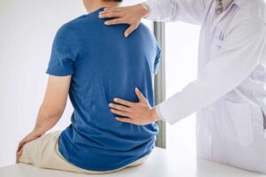 A chiropractor reviewing a health history form with a patient in a private consultation room.